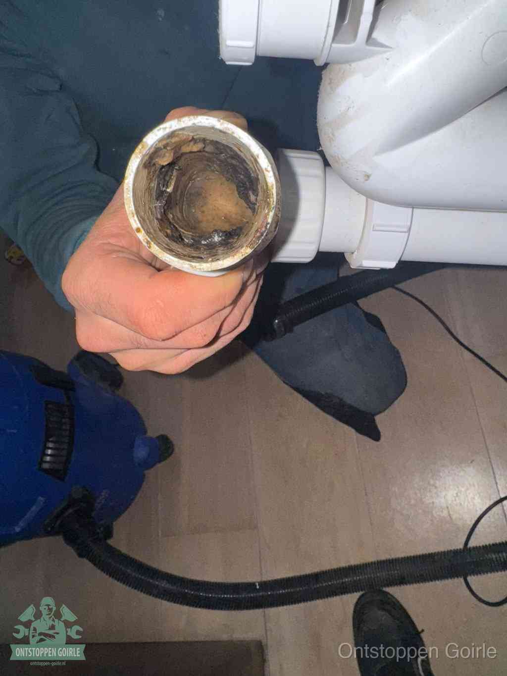 Een losgekoppeld PVC-afvoerbuisstuk dat van binnen volledig is dichtgeslibd met vet en vuil, de meest voorkomende oorzaak van verstoppingen in Goirle