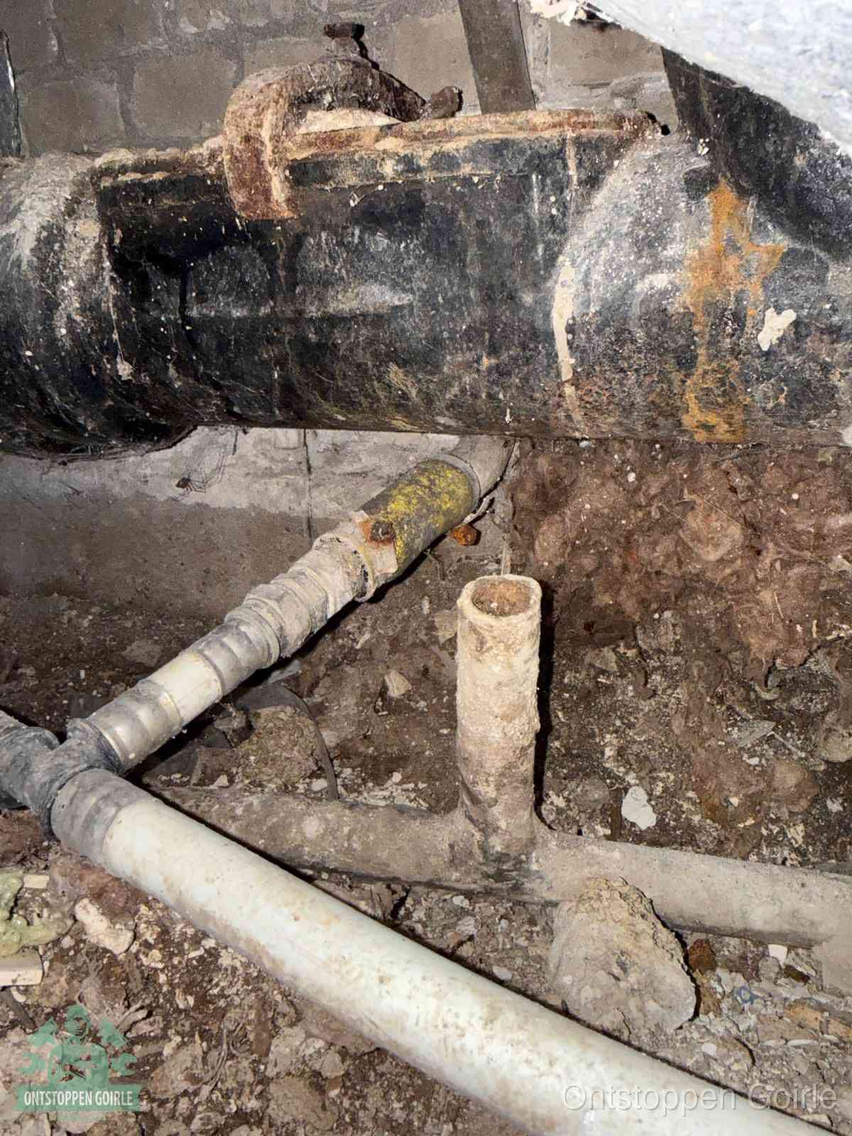 Een oude hoofdrioolbuis met roest- en kalkaanslag in een kruipruimte, oorzaak van terugkerende structurele rioolproblemen in Goirle